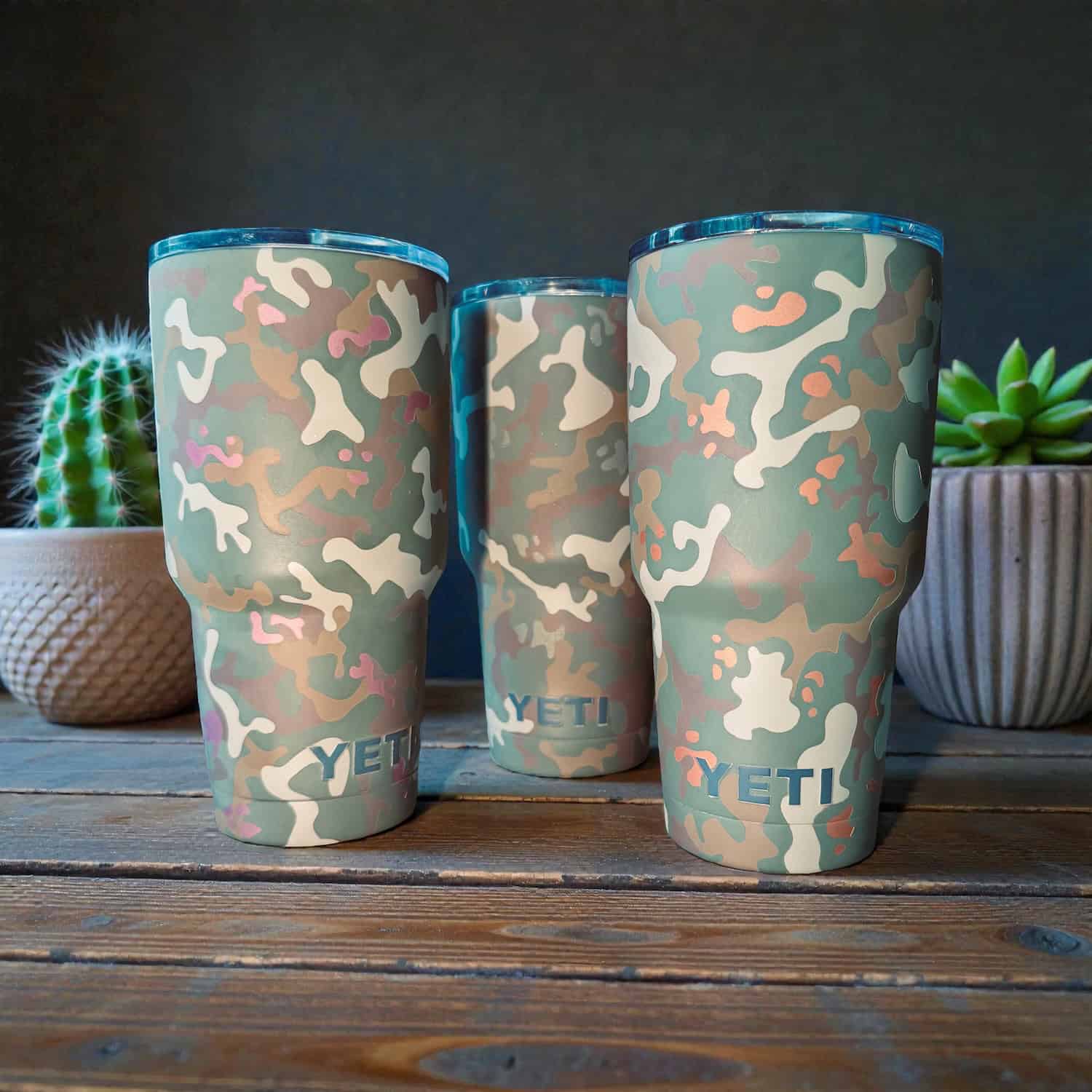 Camouflage-patterned insulated tumbler with YETI branding on a wooden surface.