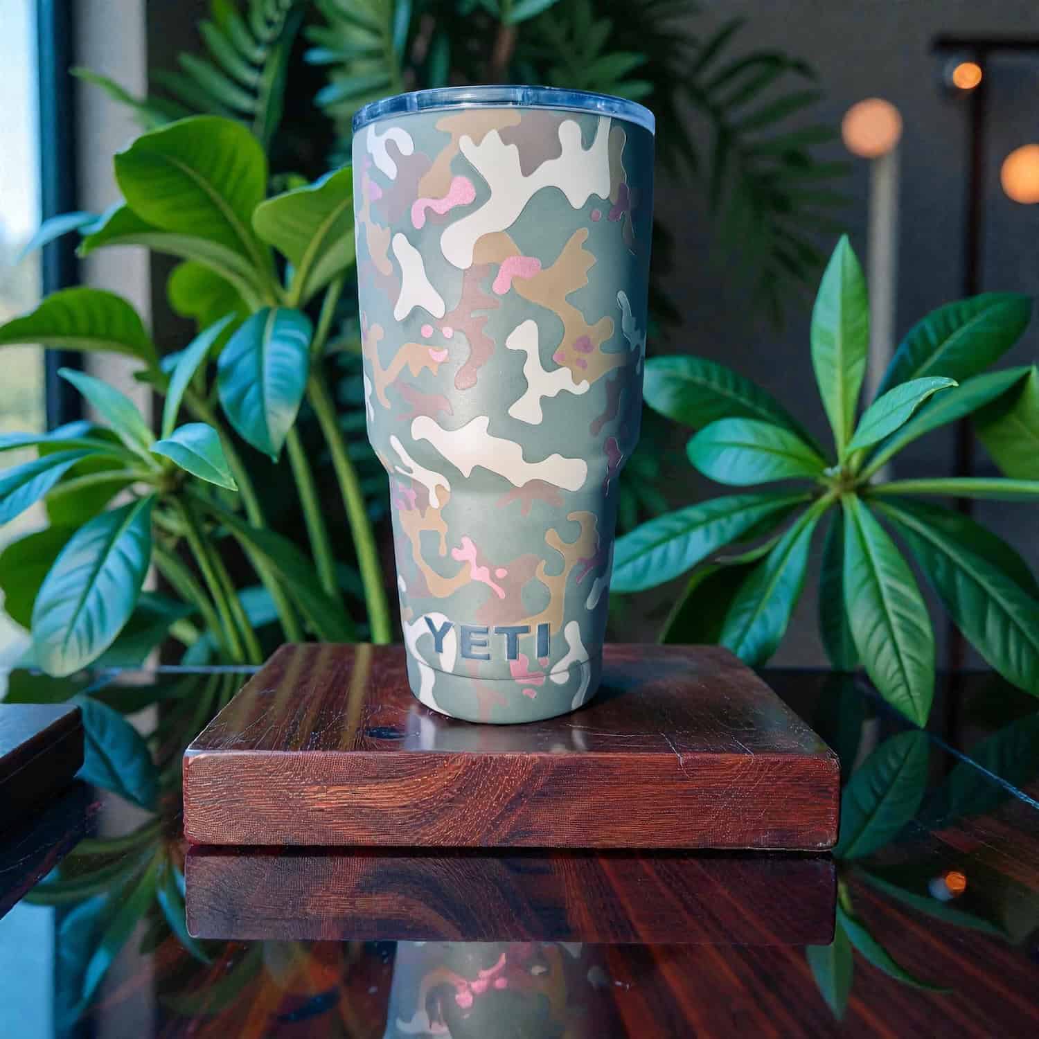 Camouflage YETI tumbler with custom firearm coating finish on a wooden surface.